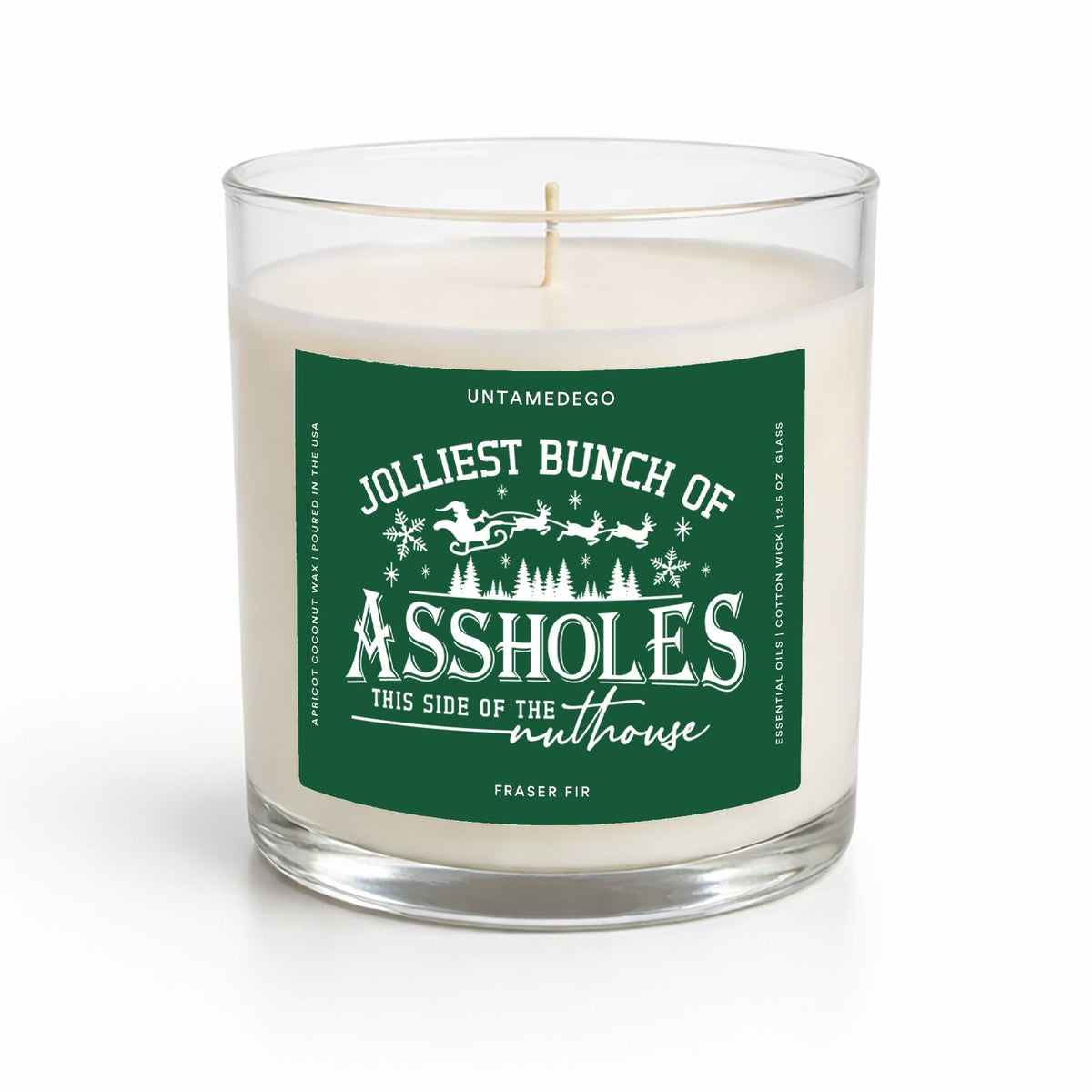 A white wax candle in a clear glass jar with a green and white label that reads 'Jolliest Bunch of Assholes This Side of the Malthouse' and 'Untamedego'.