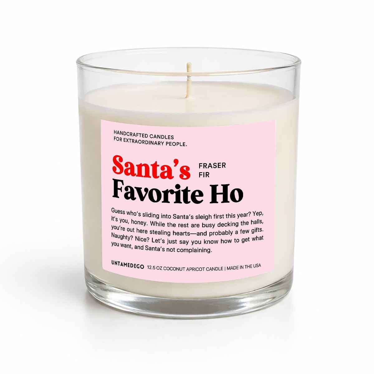 A handcrafted soy candle in a clear glass jar with a pink and white label that reads 'Santa's Favorite Ho' by Fraser Fir. The candle is photographed on a clean white background with a soft shadow.
