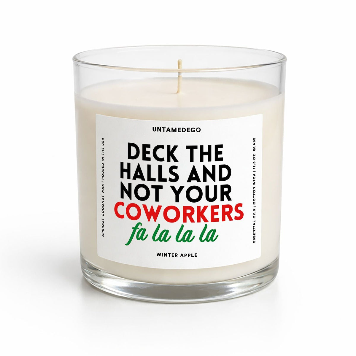 A winter-themed scented candle in a clear glass jar with a white label featuring the text 'DECK THE HALLS AND NOT YOUR COWORKERS fu la la la' in black, red, and green lettering. The candle is shown on a clean white background.