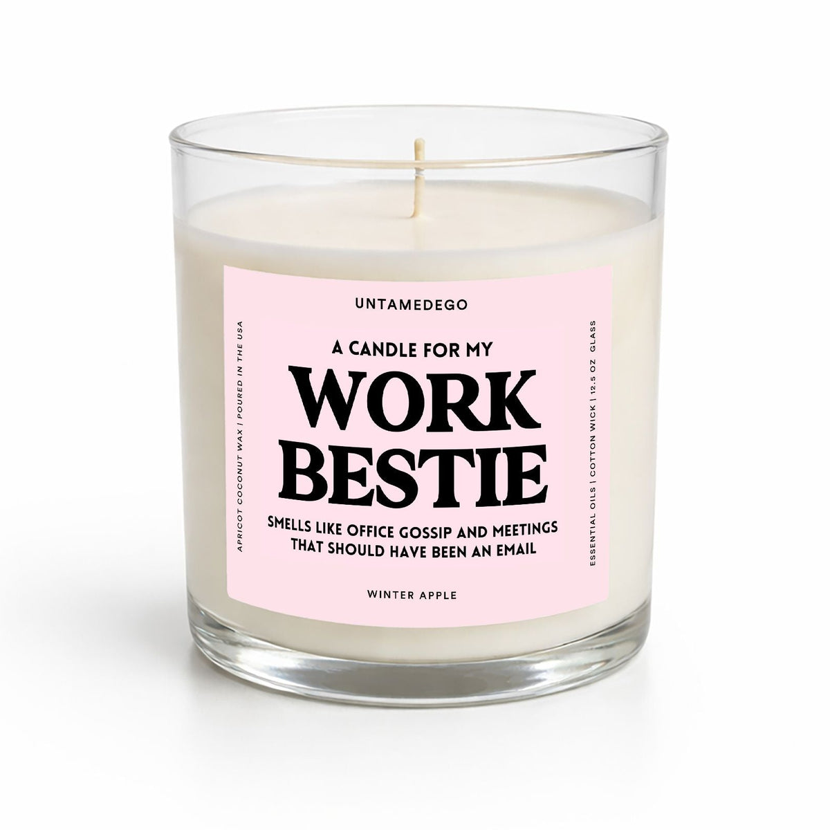 A clear glass jar candle with white wax and a light pink label that reads 'A CANDLE FOR MY WORK BESTIE' in bold black text. The brand name 'UNTAMEDEGO' is visible at the top of the label, and 'WINTER APPLE' appears at the bottom.