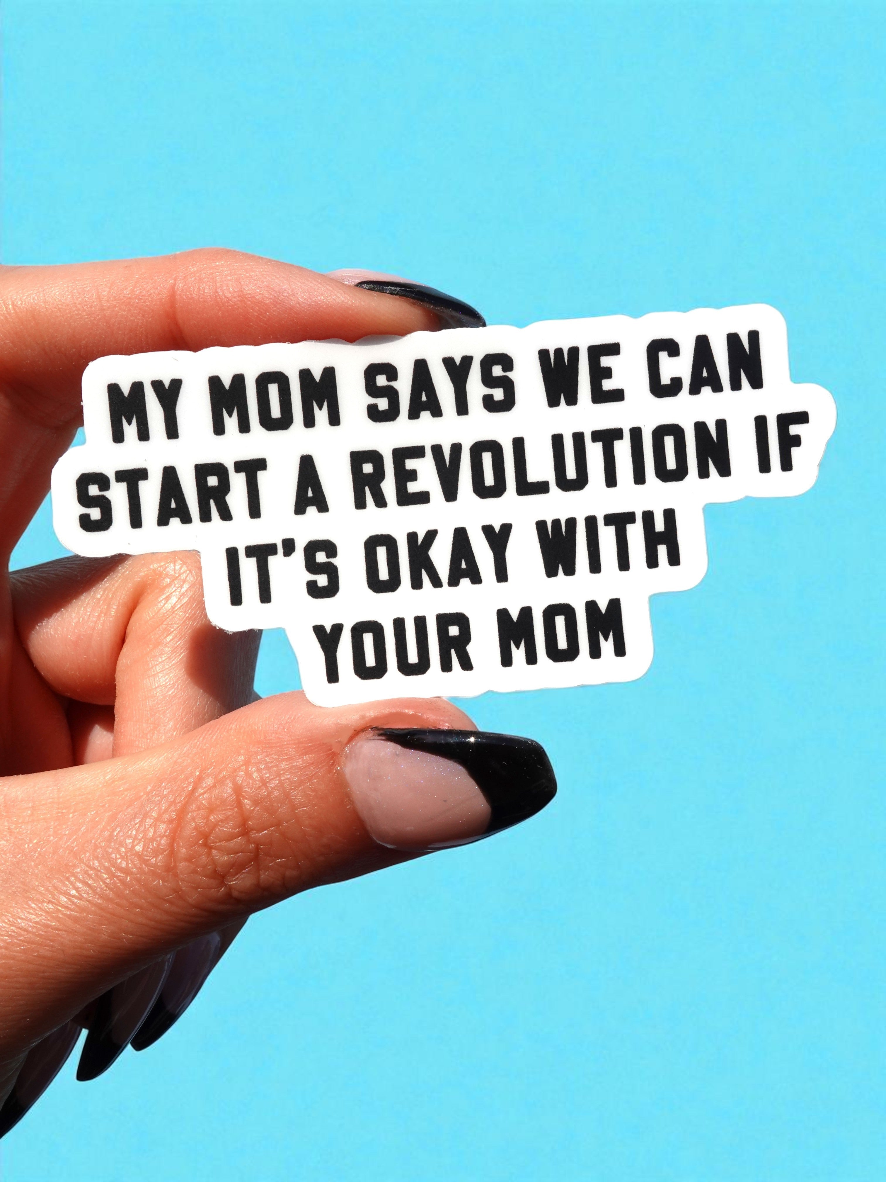Hand holding a sticker with text against a blue background