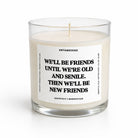 A clear glass jar candle with white wax and a white label featuring black text that reads, 'WE'LL BE FRIENDS UNTIL WE'RE OLD AND SENILE. THEN WE'LL BE NEW FRIENDS.