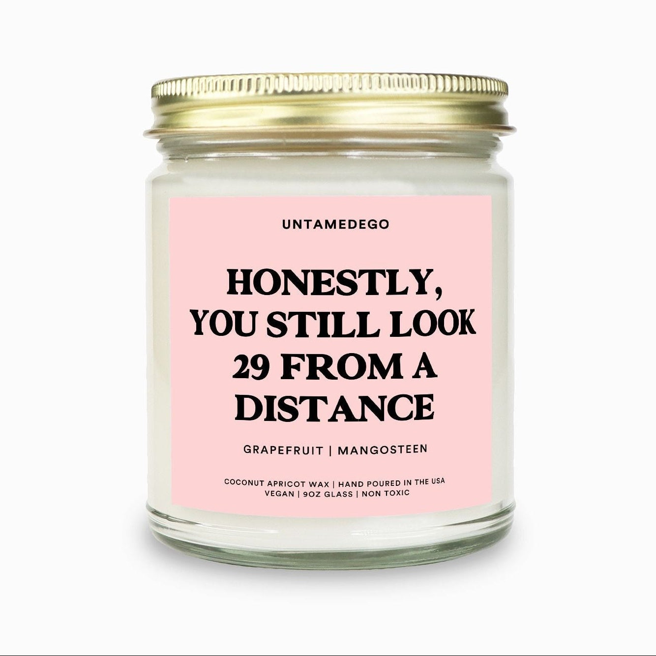 Candle with pink label and gold lid on a white background