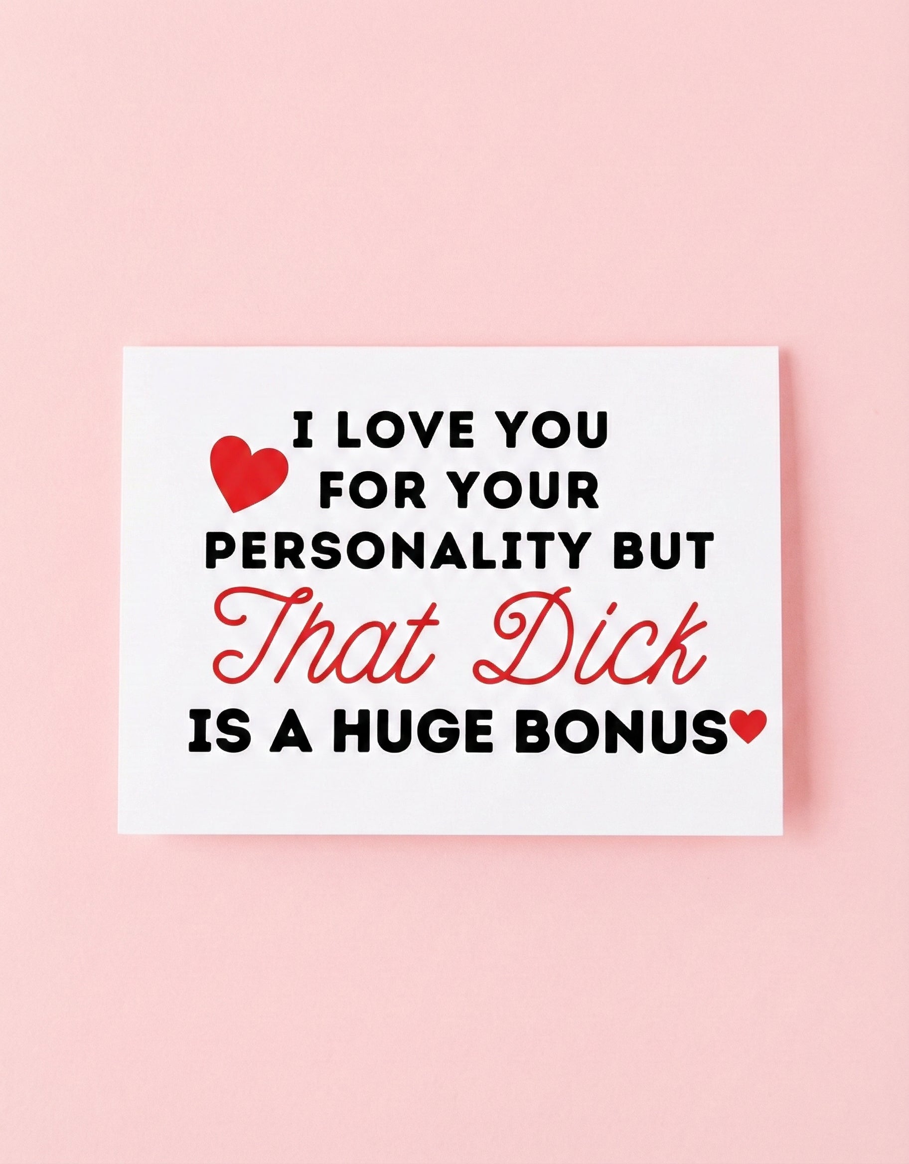 Greeting card displaying a humorous adult phrase in black and red text with heart graphics, photographed against a pink background
