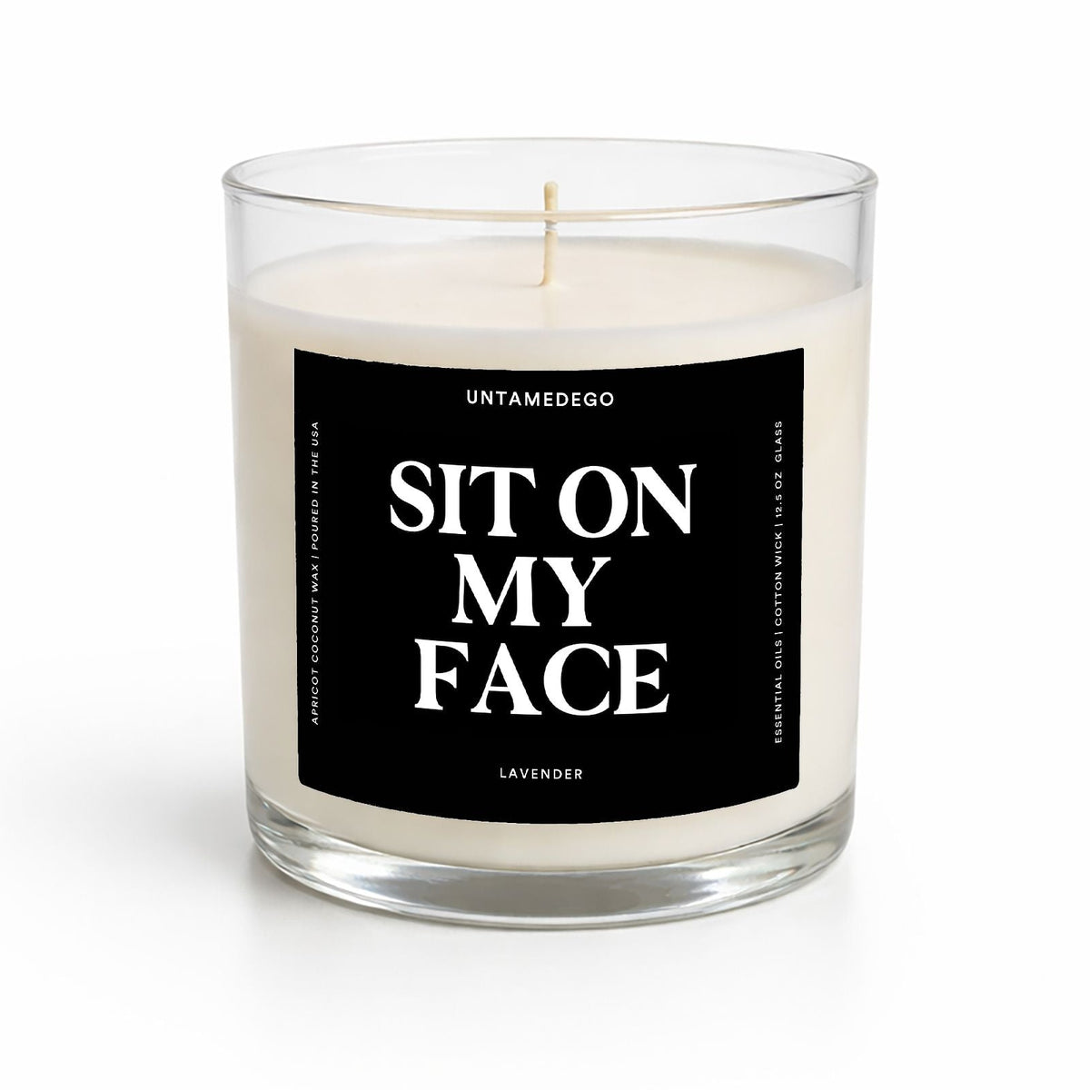 A clear glass jar candle with white wax and a black front label reading 'SIT ON MY FACE' in large white text. The brand name 'UNTAMEDEGO' is visible at the top of the label, with 'LAVENDER' at the bottom.
