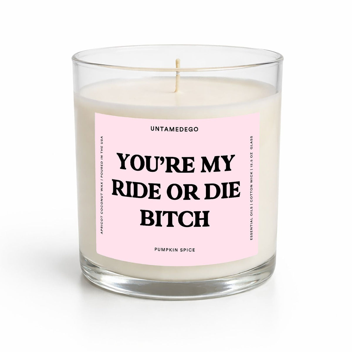 A single-wick soy candle in a clear glass jar with a pale pink label that reads 'YOU'RE MY RIDE OR DIE BITCH' in bold black text. The brand name 'UNTAMEDEGO' is visible at the top of the label, and 'PUMPKIN SPICE' is written at the bottom.
