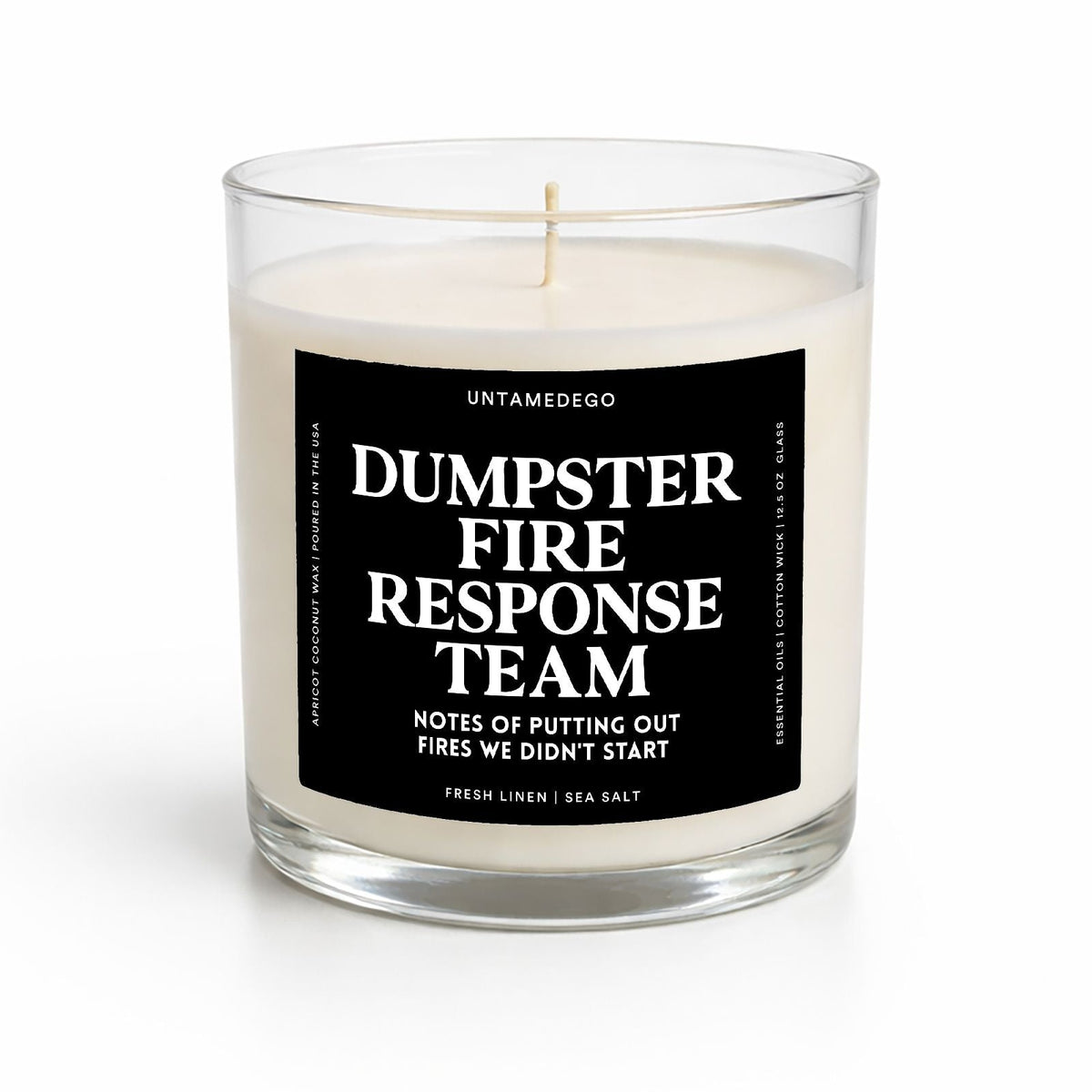 A clear glass jar candle with white wax and a black label reading 'DUMPSTER FIRE RESPONSE TEAM' in white text, photographed on a clean white background.