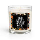 A clear glass jar candle with white wax and a single wick, featuring a black front label with white text that reads 'I LIKE SPOOKY THINGS & THE WORD FUCK' and a colorful Halloween-themed border with pumpkins, ghosts, and spiders. The candle is photographed on a clean white background.