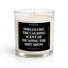 A clear glass jar candle with white wax and a black label featuring bold white text that reads, 'SMELLS LIKE THE CALMING SCENT OF ESCAPING THE SHIT SHOW.' The brand name 'UNTAMEDEGO' is visible at the top of the label.
