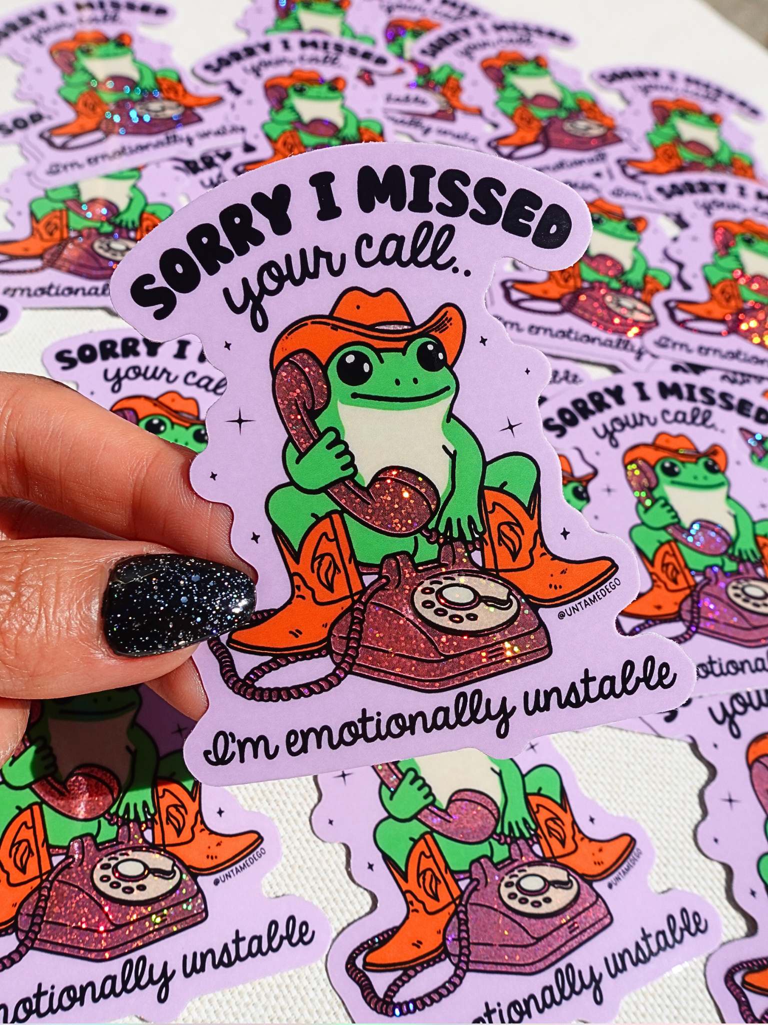Sticker with a frog in cowboy boots and hat holding a phone, surrounded by more similar stickers.