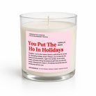 A handcrafted soy candle in a clear glass jar with a white wax fill and a pink label that reads 'You Put The Ho In Holidays' and 'Vanilla Bean'.