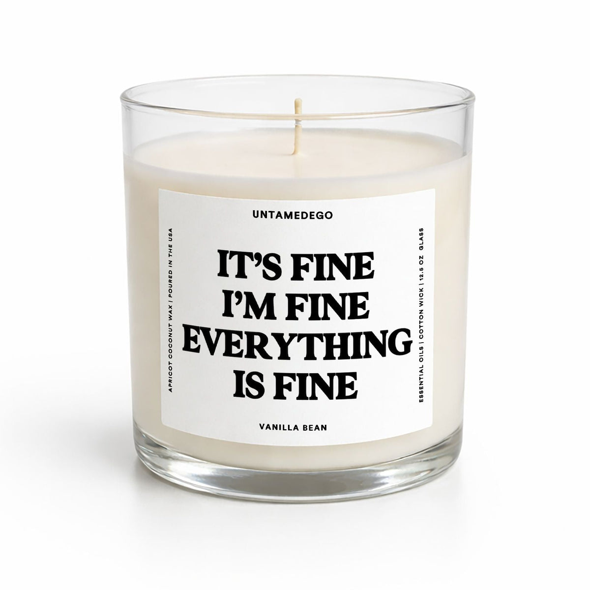 A clear glass jar candle with white wax and a white label that reads 'IT'S FINE I'M FINE EVERYTHING IS FINE' in bold black text. The brand name 'UNTAMEDEGO' is visible at the top of the label, with 'VANILLA SEAN' at the bottom.