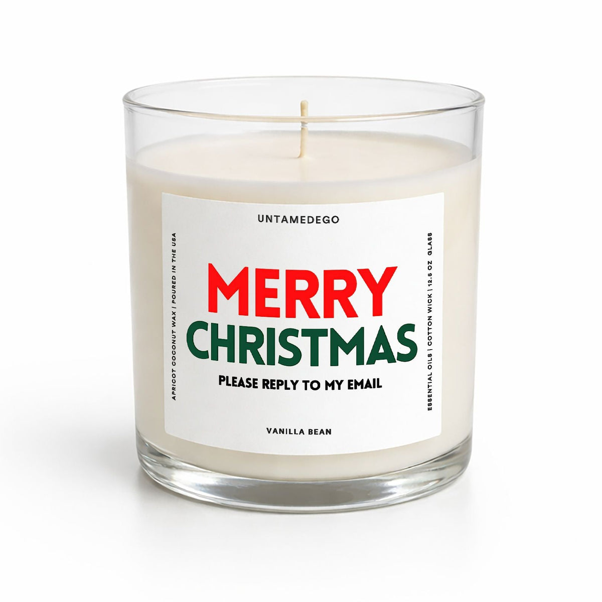A personalized holiday candle in a clear glass jar with white wax and a single wick. The front features a white label with the text 'MERRY CHRISTMAS' in red and green, and 'VANILLA BEAN' at the bottom.