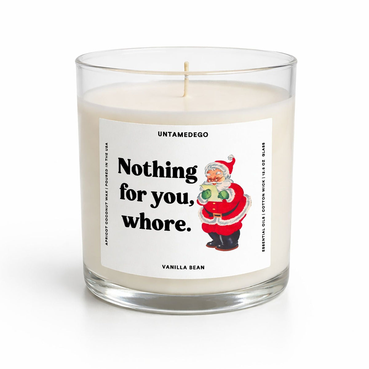 A clear glass jar candle with white wax and a printed front label reading 'Nothing for you, whore.' with a Santa illustration.