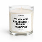 A single-wick candle in a clear glass jar with cream-colored wax and a white label featuring bold black text that reads 'THANK YOU FOR BEING MY UNPAID THERAPIST' with 'UNTAMEDOGO' at the top and 'VANILLA BEAN' at the bottom.