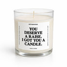 A single-wick candle in a clear glass jar with cream-colored wax and a white label featuring black text that reads, 'YOU DESERVE A RAISE. I GOT YOU A CANDLE.