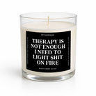 A clear glass jar candle with white wax and a black label featuring bold white text that reads, 'THERAPY IS NOT ENOUGH I NEED TO LIGHT SHIT ON FIRE.' The brand name 'UNTAMEDEGO' is visible at the top of the label, and 'ESPRESSO' appears at the bottom.