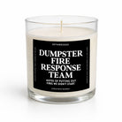 A clear glass jar candle with cream-colored wax and a black label that reads 'DUMPSTER FIRE RESPONSE TEAM' in white text, photographed on a clean white background.