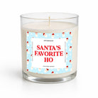 A clear glass jar candle with white wax and a festive label that reads 'SANTA'S FAVORITE HO' in red text on a light blue background with Santa illustrations, photographed on a clean white background.