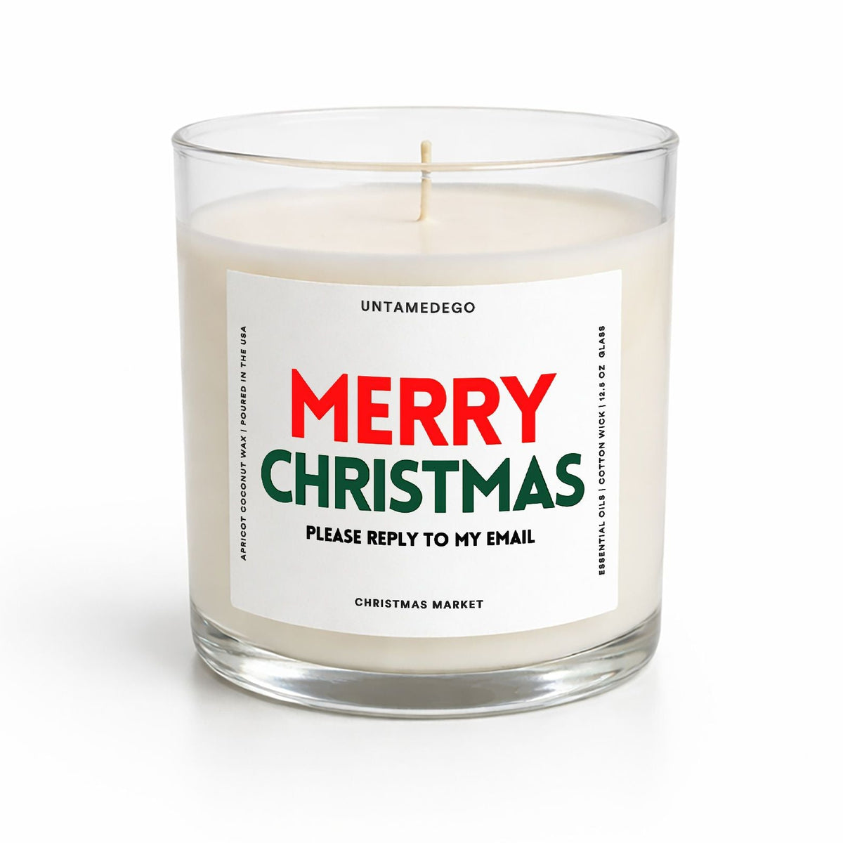A white wax candle in a clear glass jar with a humorous 'Merry Christmas Please Reply to My Email' label by Untamedego, shown on a clean white background.