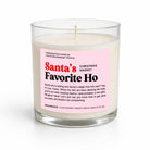 A handcrafted soy candle in a clear glass jar with a wick, featuring a pink label that reads 'Santa's Favorite Ho' and 'Christmas Market' by Unsanded. The candle is photographed on a clean white background with a soft shadow.