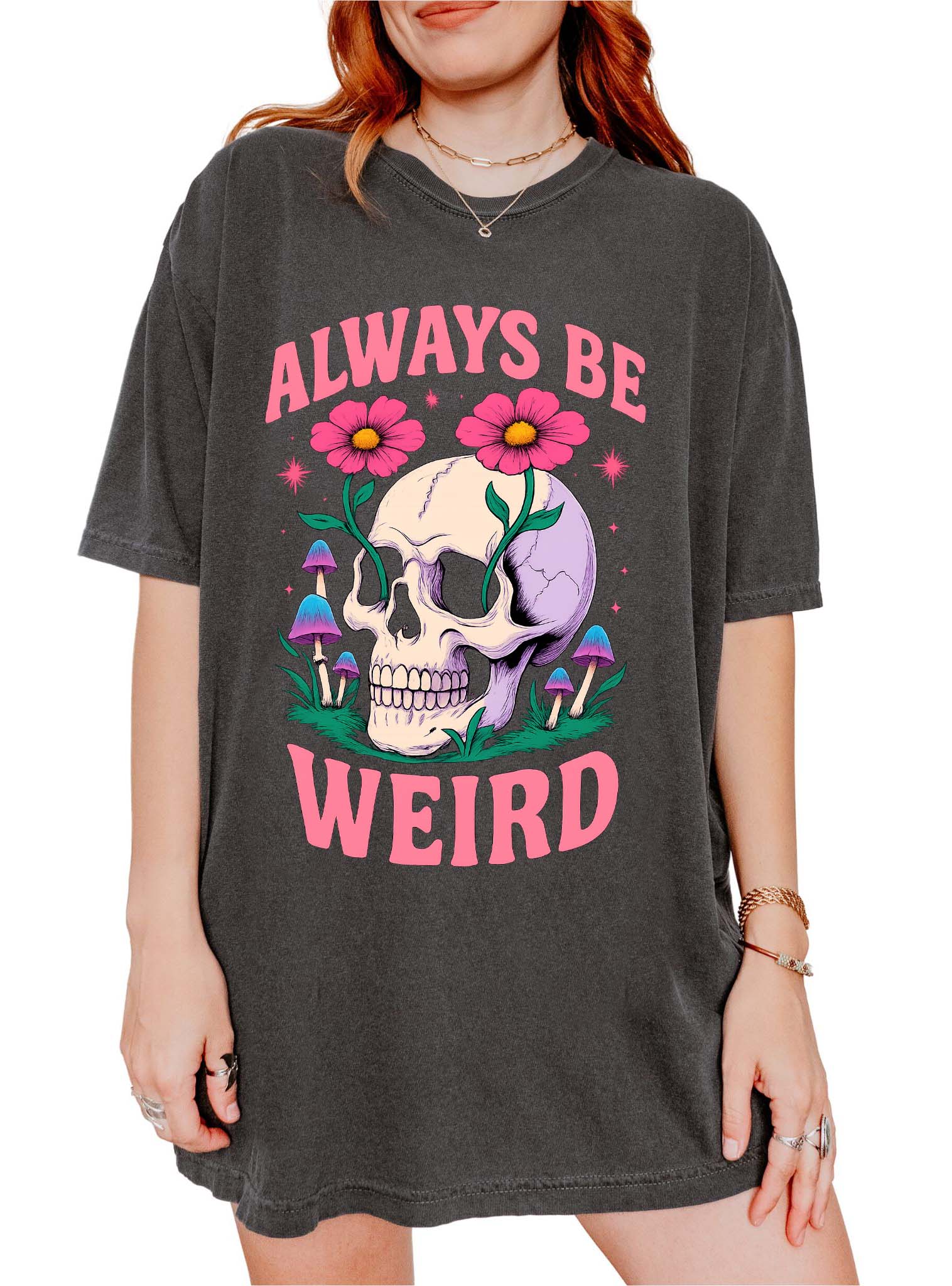 Graphic t-shirt with skull, flowers, and mushrooms design and text saying always be weird