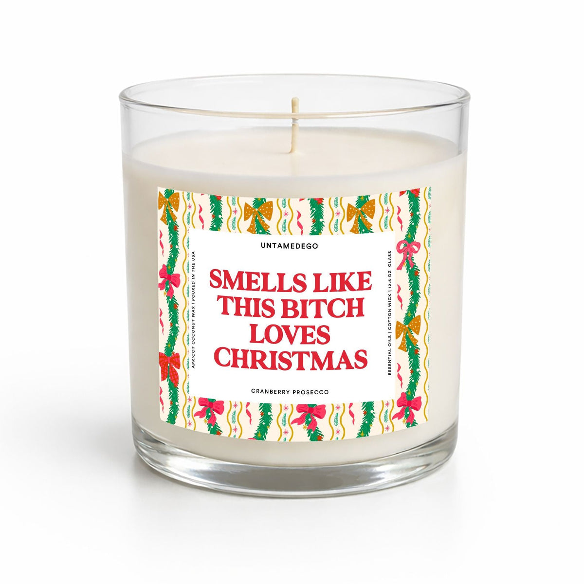 A clear glass jar candle with white wax and a humorous Christmas-themed label that reads 'SMELLS LIKE THIS BITCH LOVES CHRISTMAS' in red text, shown on a clean white background.