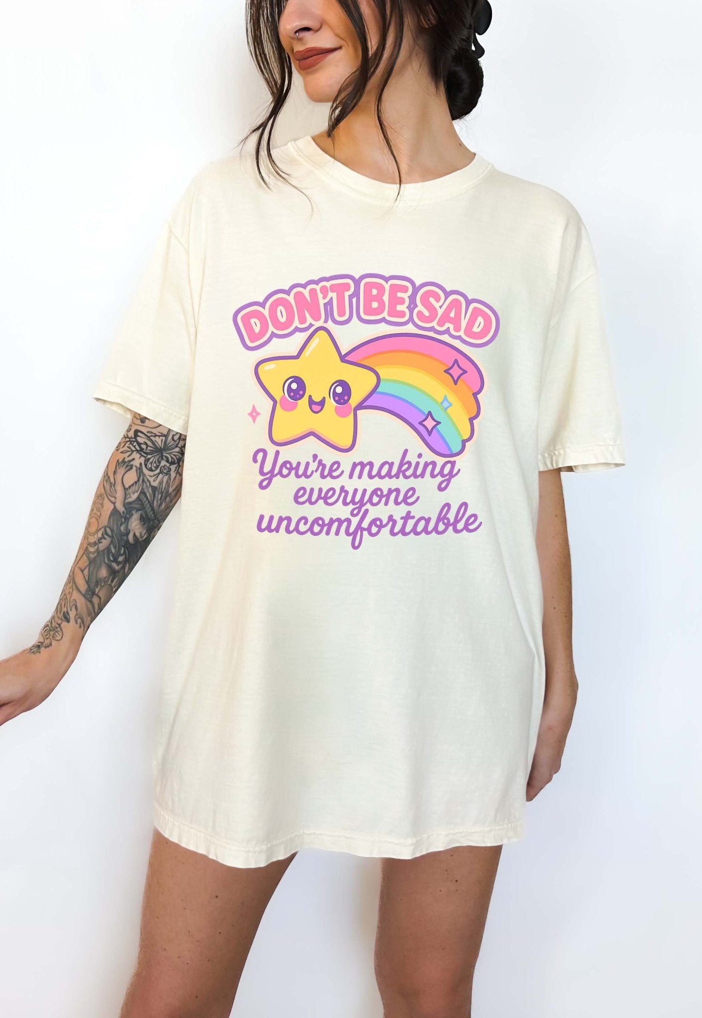 Funny graphic t-shirt with cute star and rainbow design and text saying don’t be sad you’re making everyone uncomfortable