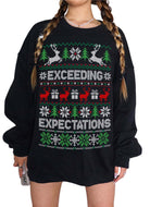 A person wearing an oversized black long-sleeve sweatshirt with a festive Christmas sweater print featuring reindeer, trees, snowflakes, and the words 'EXCEEDING EXPECTATIONS' in white, green, and red.