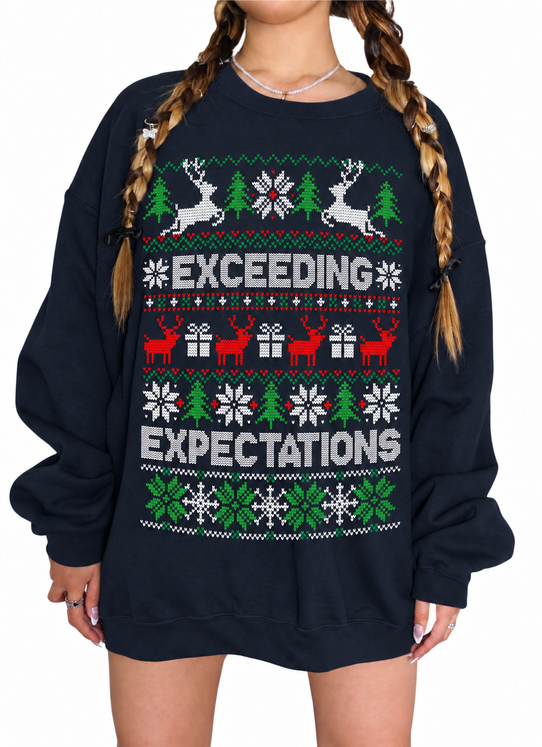 A person wearing an oversized navy crewneck sweatshirt with a festive Christmas sweater print featuring the words 'EXCEEDING EXPECTATIONS' in white, with green and red holiday motifs including reindeer, trees, snowflakes, and gift boxes.
