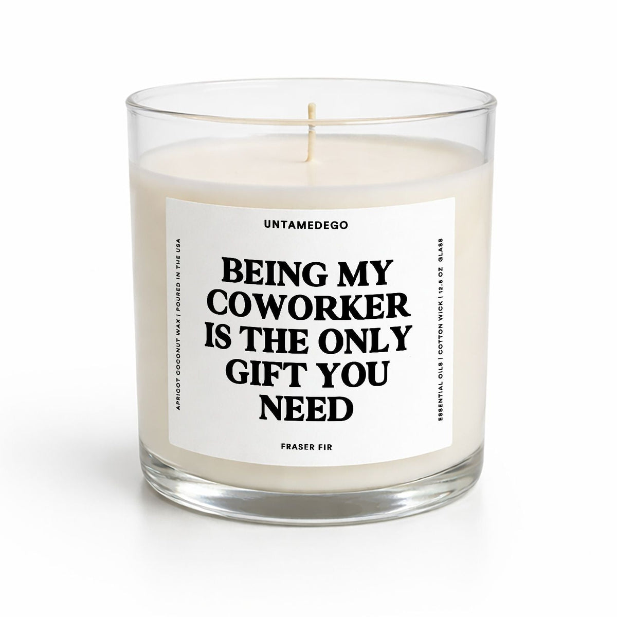 A clear glass jar candle with cream-colored wax and a single wick, featuring a white label with bold black text that reads 'BEING MY COWORKER IS THE ONLY GIFT YOU NEED.' The brand name 'UNTAMEDEGO' is visible at the top of the label.