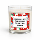 A clear glass jar candle with white wax and a humorous Christmas-themed label that reads 'SMELLS LIKE CHRISTMAS UP IN THIS BITCH.' The label features a red border with cartoon snowman illustrations and the brand name Untamed Co.