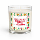 A clear glass jar candle with white wax and a humorous Christmas-themed label that reads 'SMELLS LIKE THIS BITCH LOVES CHRISTMAS' in red text, surrounded by green holly and red bows, on a white background.