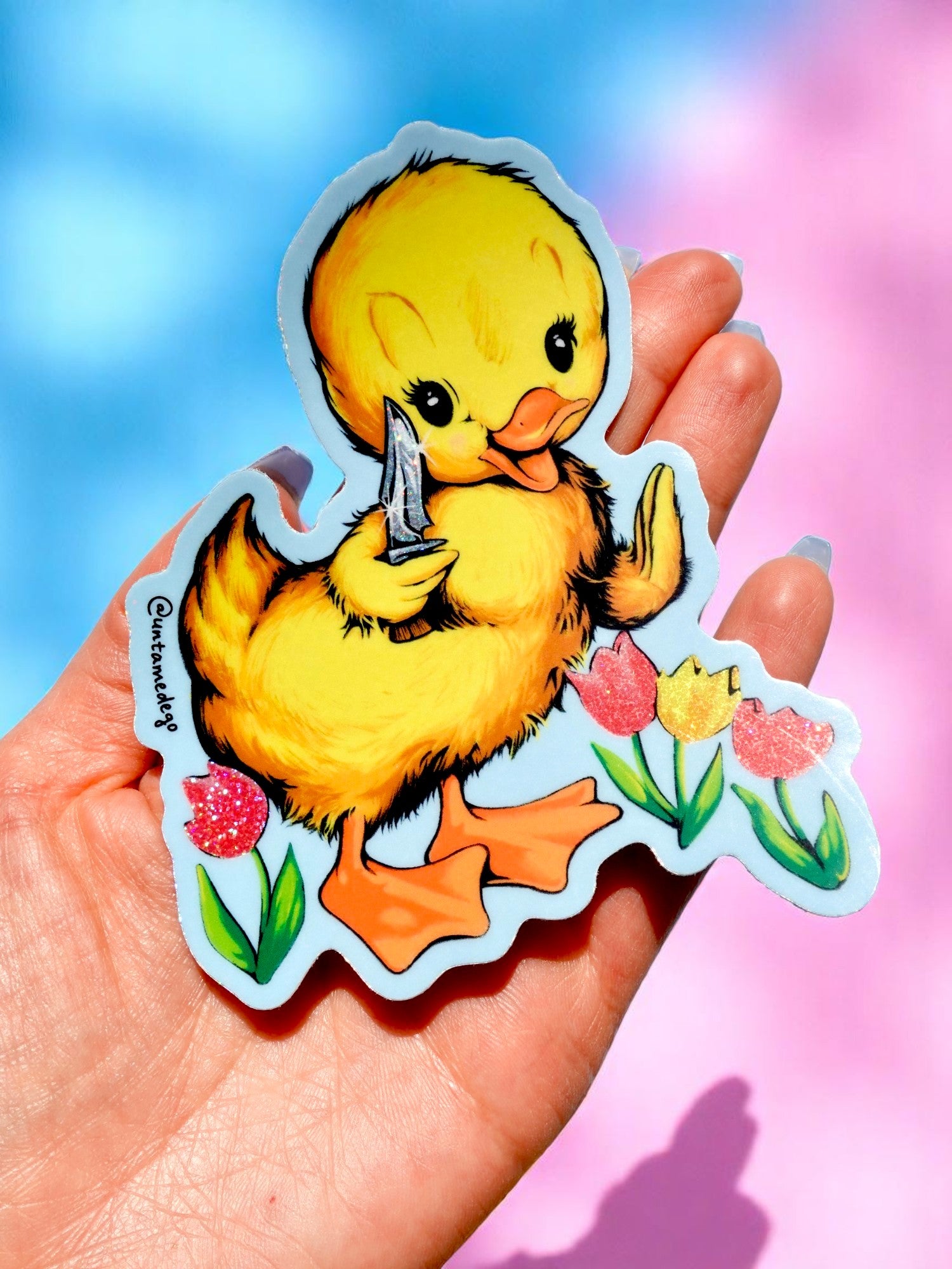 Funny vinyl sticker of a cute yellow duck holding a knife, standing among glitter tulips. Dark humor waterproof sticker with pastel aesthetic.