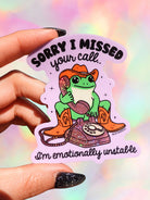 Sticker with a frog in a cowboy hat and boots holding a phone, text 'Sorry I missed your call. I'm emotionally unstable' on a colorful background.