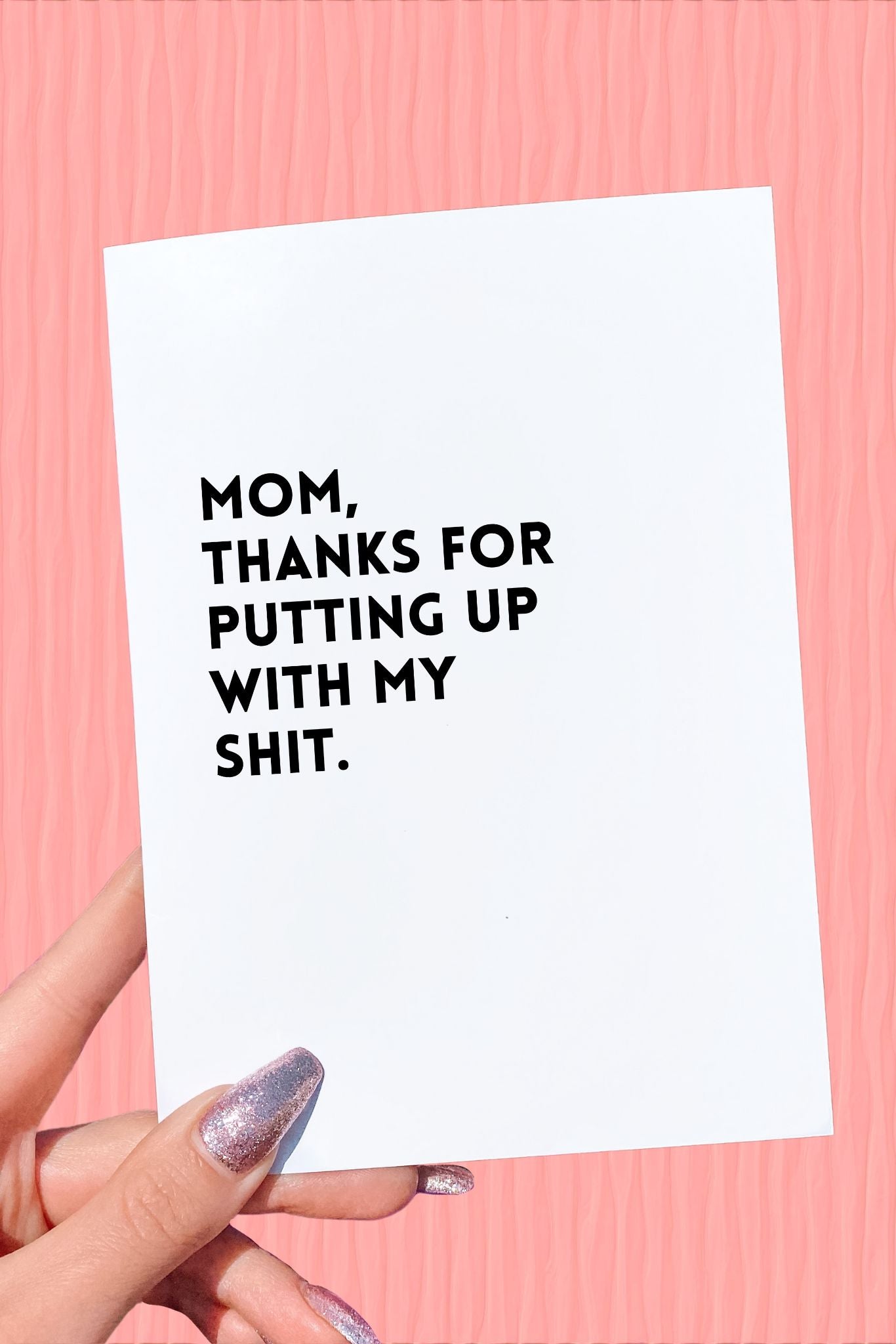 A person holding a Mother's Day card with a text message, against a pink background.