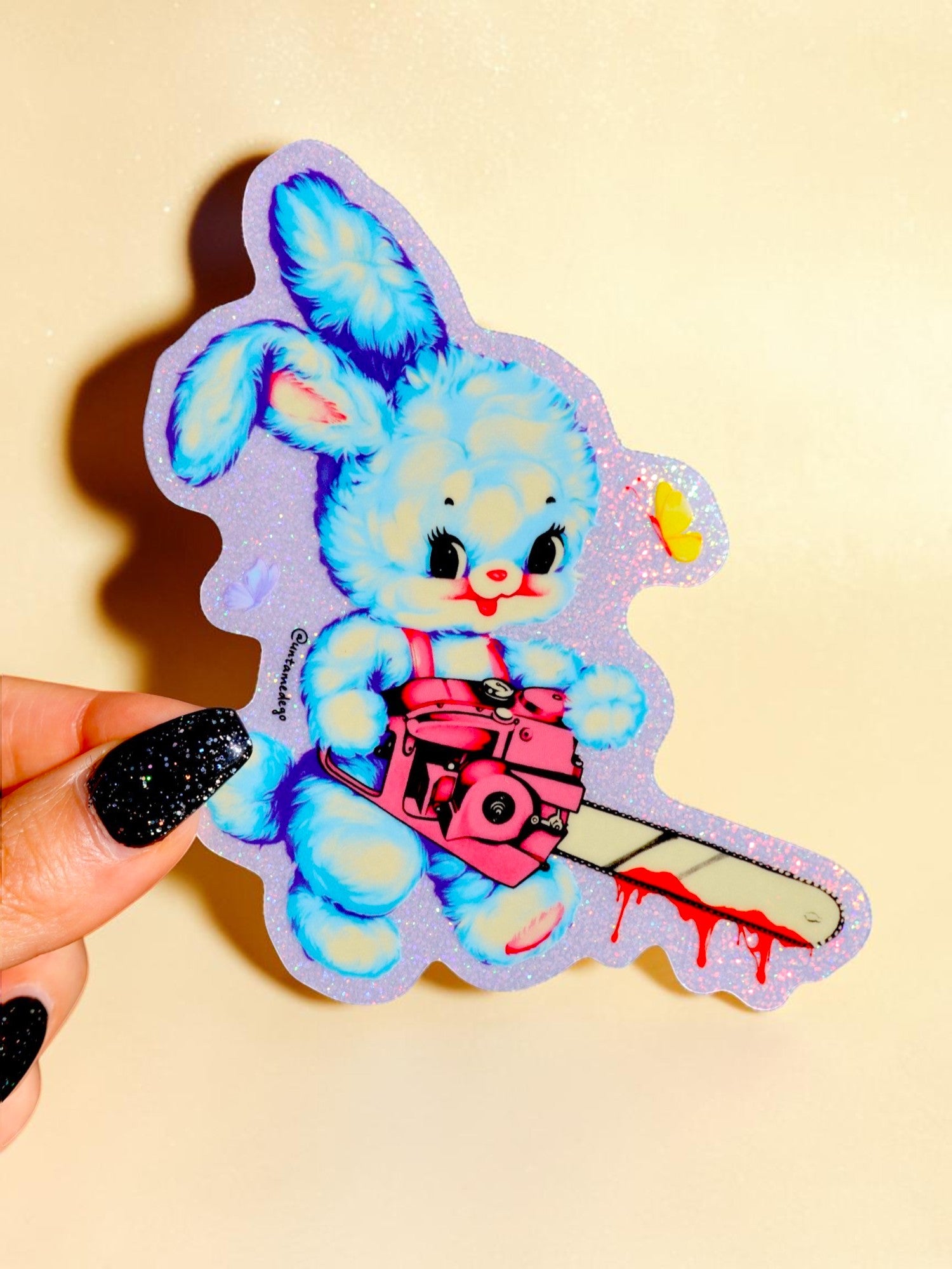 Sticker of a blue bunny holding a knife on a beige background