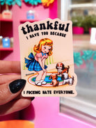 Die-cut glossy vinyl sticker featuring a retro-style illustration of a blonde girl in a blue dress sitting on a rug with two puppies. Text reads: Thankful I Have You Because I Fucking Hate Everyone.