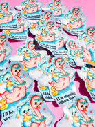 Holographic die-cut sticker reading "I'll be choosing violence today" held by a hand with light blue nails against a pink background, shown alongside multiple stickers scattered on a pink surface.