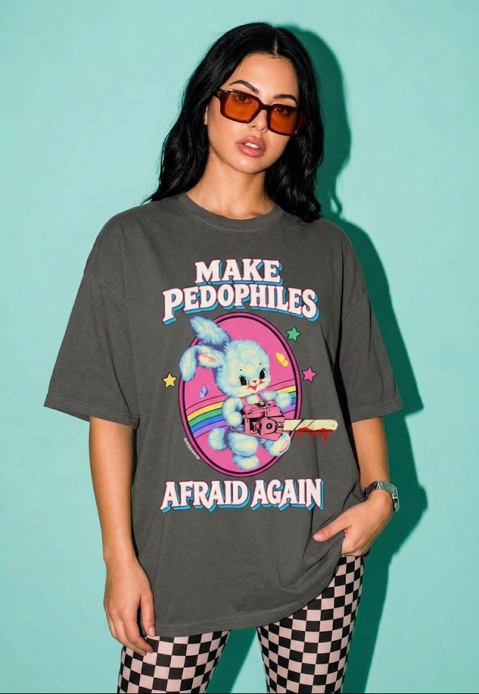 A woman modeling a dark gray graphic t-shirt with a cartoon bunny and the text 'MAKE PEDOPHILES AFRAID AGAIN' against a solid teal background.