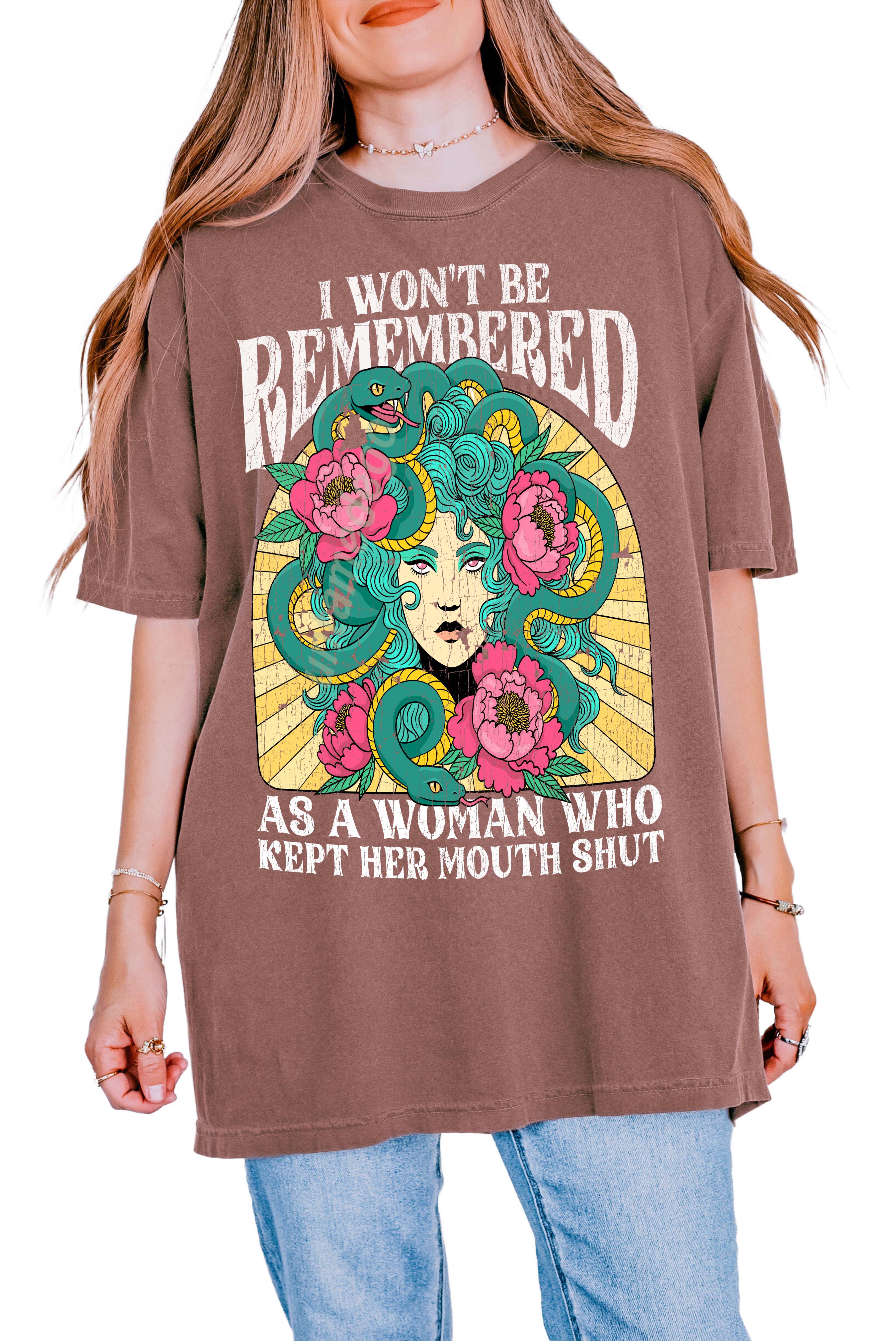 A woman modeling a white crew neck t-shirt with a graphic print in the center that reads 'I Won't Be Remembered As A Woman Who Kept Her Mouth Shut' surrounded by floral designs.