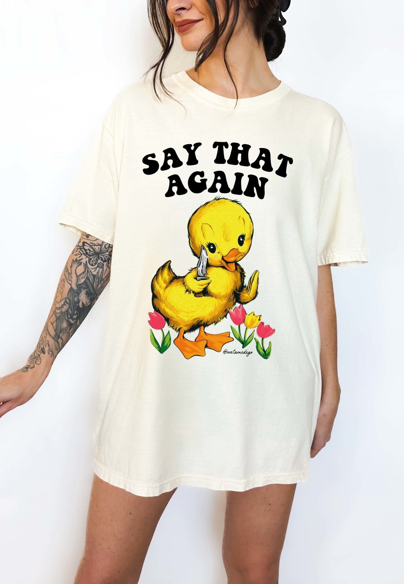 Funny graphic t-shirt with cute duck holding knife and text saying say that again