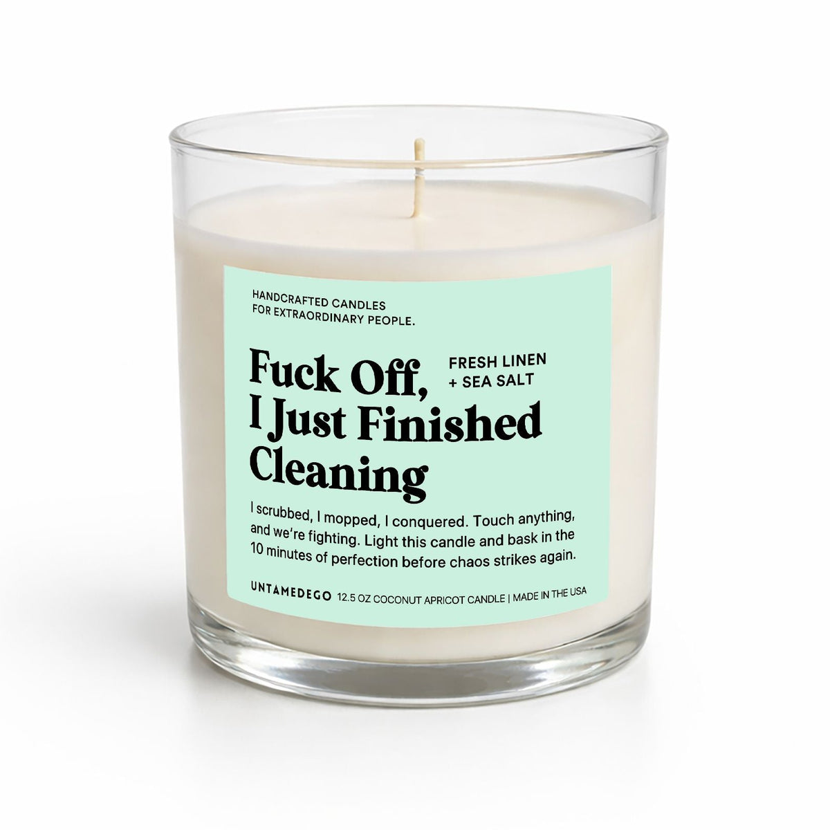 A 12.5 oz soy candle in a clear glass jar with a humorous label that reads 'F*ck Off, I Just Finished Cleaning' by Antamereo, on a white background.