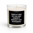 A clear glass jar candle with white wax and a black label featuring bold white text that reads, 'SMELLS LIKE MY SALARY DOESN'T REFLECT MY SUFFERING.' The brand name 'UNTAMEDEGO' is visible at the top of the label.