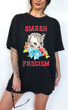 Graphic t-shirt with cute cat illustration and bold protest text reading smash fascism