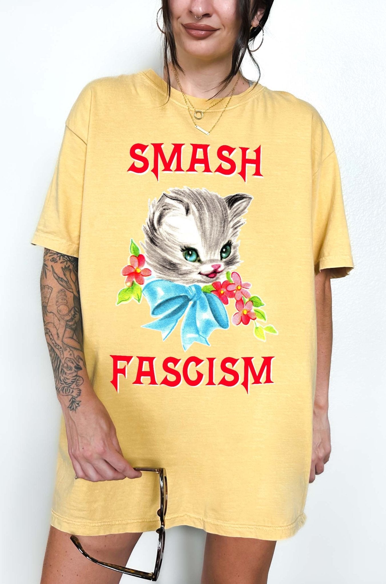 Graphic t-shirt with cute cat illustration and bold protest text reading smash fascism