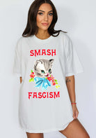 Graphic t-shirt with cute cat illustration and bold protest text reading smash fascism