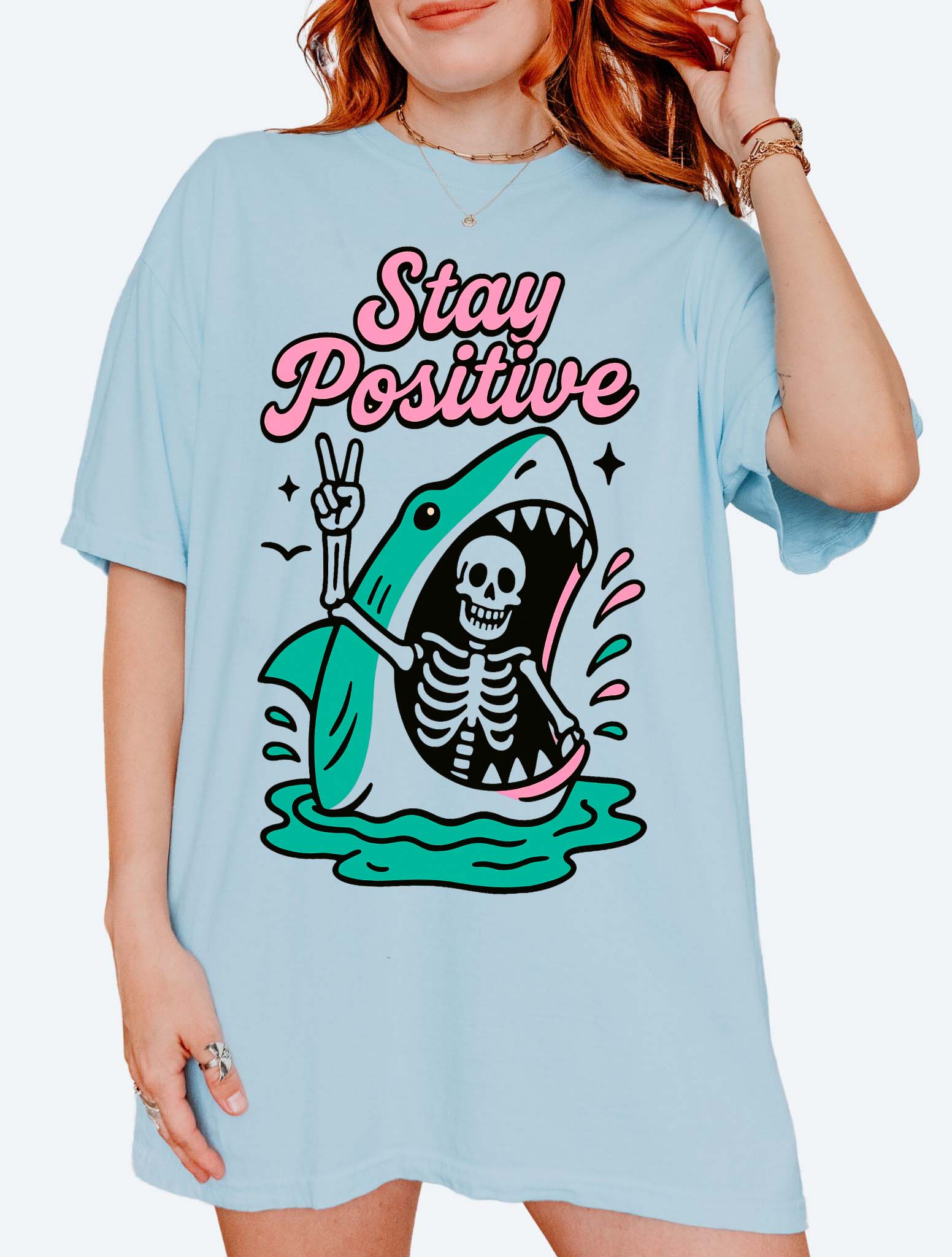 Funny graphic t-shirt with skeleton inside shark illustration and text saying stay positive