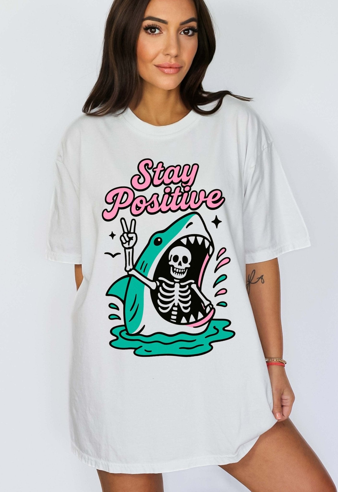 Funny graphic t-shirt with skeleton inside shark illustration and text saying stay positive