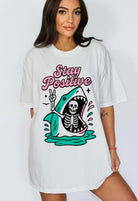 Funny graphic t-shirt with skeleton inside shark illustration and text saying stay positive